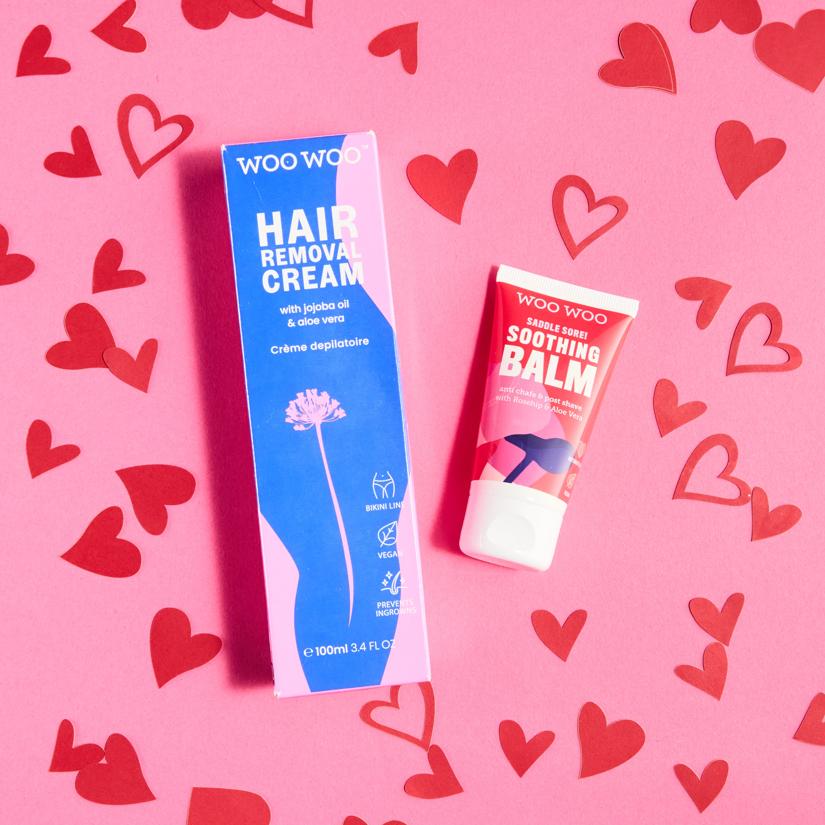 Woo Woo hair removal cream and balm on a pink background with red hearts