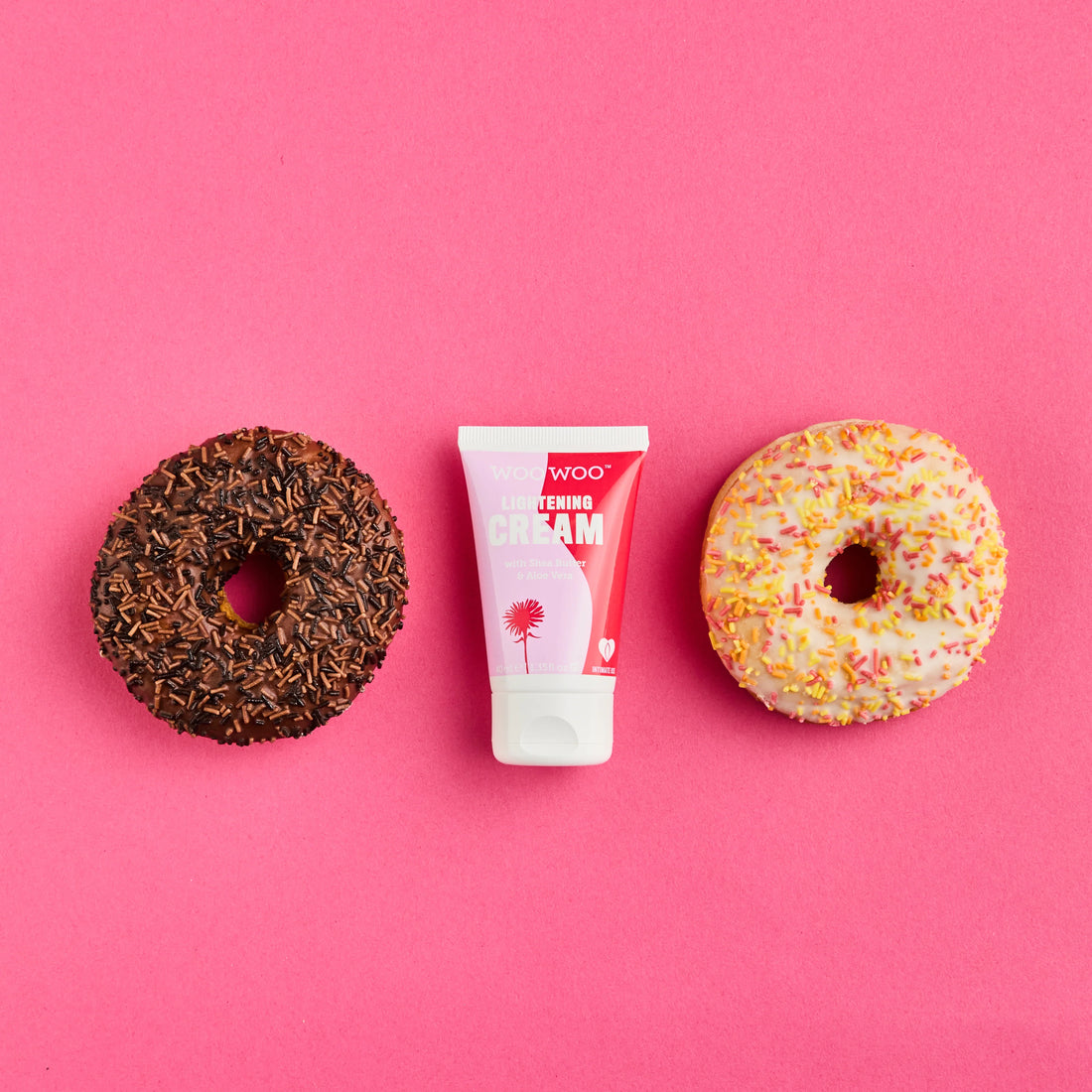 Two donuts and a tube of cream on a pink background